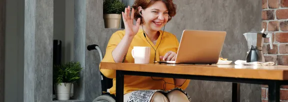 Woman in Orange Tank Top Sitting on Black Wheelchair using Laptop