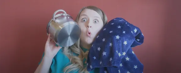 Claire holds up a cooking pot and blanket to her cheeks