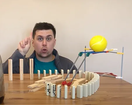 Ross looks on at his Rube Goldberg machine which includes dominoes, a giant tennis ball, electric kettle and ramp.