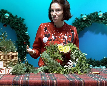 A science communicator wearing a Christmas jumper makes a Christmas wreath
