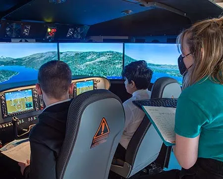 Pupils and flight instructor at the controls of a flight simulator