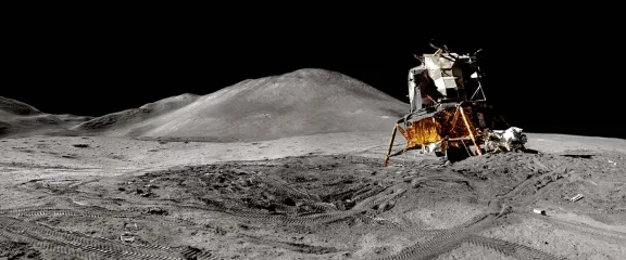 A lunar vehicle on the surface of the moon. There are tracks on the surface of the Moon and in the distance a hill. Image credit: Andy Saunders / NASA