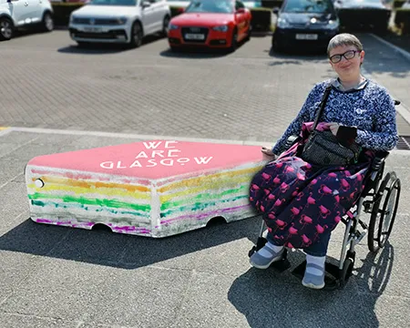 A person in a wheelchair beside a colourfully-painted bollard