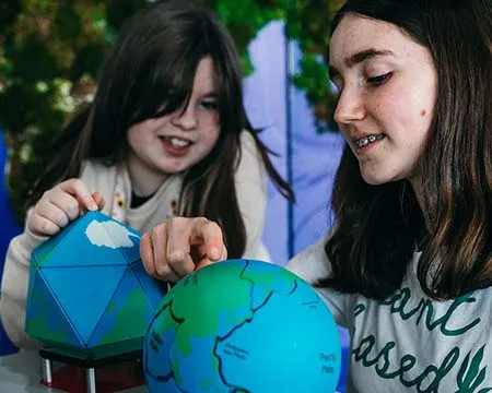 Two young people explore the pieces of a 3D jigsaw globe