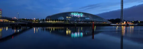 Glasgow Science Centre is illuminated against the night on the banks of the River Clyde.