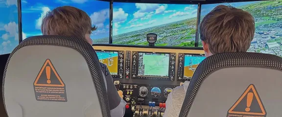 Two air cadets at the controls of a full motion flight simulator