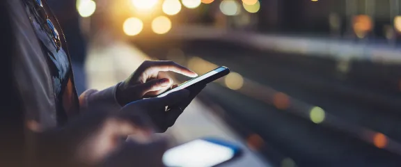 A person using a mobile phone at night on a trains station platform