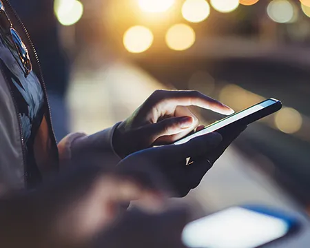 A person using a mobile phone at night on a trains station platform