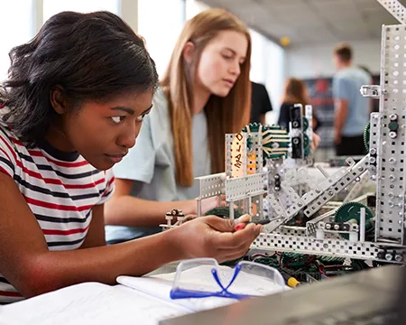 Two Female College Students Building Machine In Science Robotics Or Engineering Class