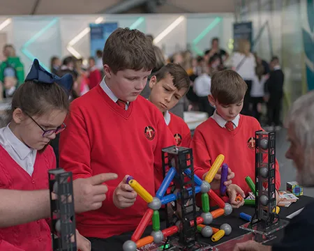 A group of school children engage with an expert at an activity table