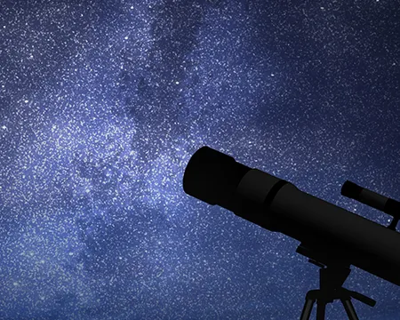 A silhouette of a telescope against a starry sky