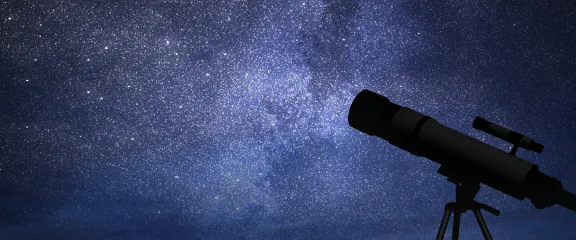 A silhouette of a telescope against a starry sky