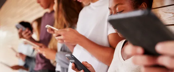 A row of students holding mobile smart phones