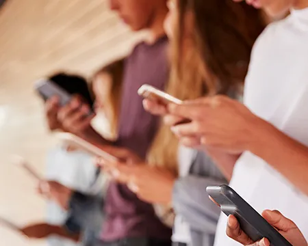 A row of students holding mobile smart phones