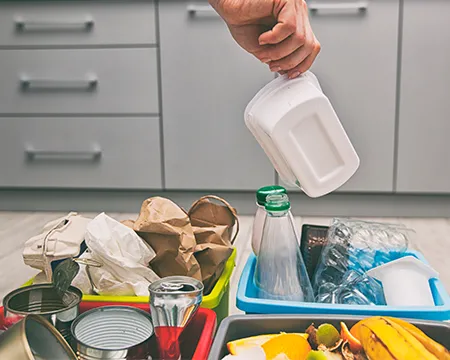 Person puts plastic container to one of four containers arranging their rubbish for recycling