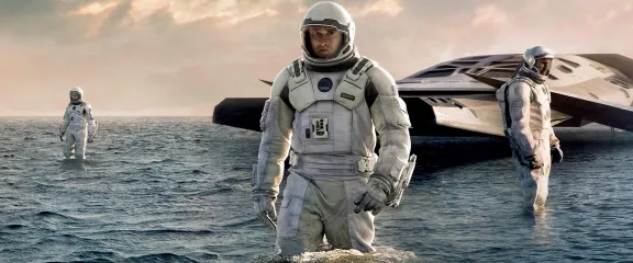 Two astronauts emerge from a spacecraft that's landed on water