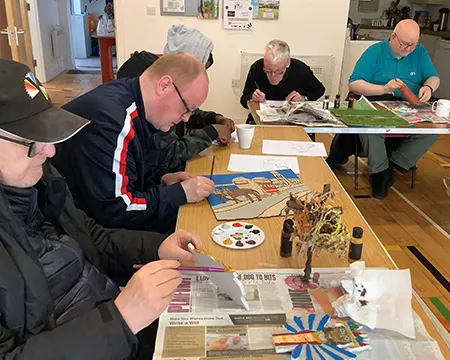 five men's group members concentrating on painting their art pieces