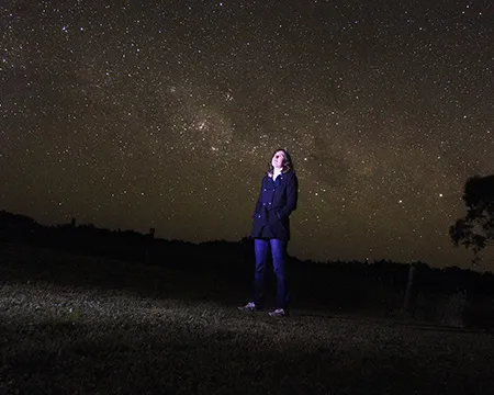 Dr Katie Mack looking upwards at a starry night sky