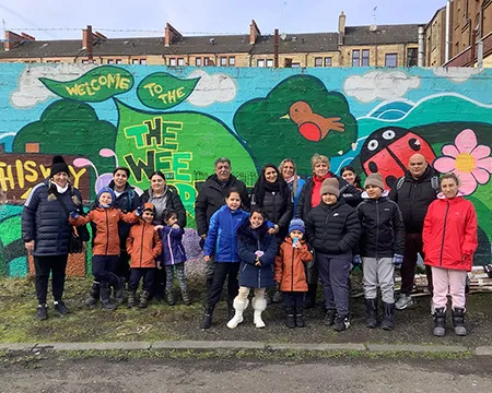 Participants in The Roots Project stand alongside the colourfully painted wall at the Wee Forest