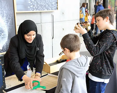 An expert engages young visitors in navigation instruments at a public engagement event