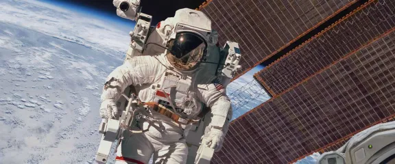 An astronaut on a space walk with the ISS and Earth in background