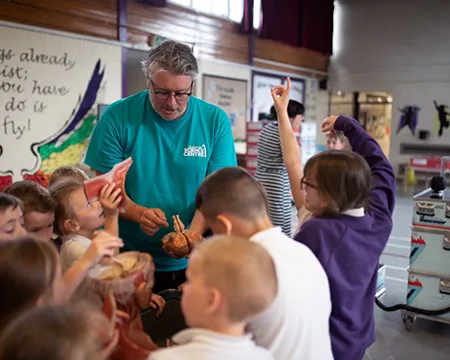 Pupils in a school hall gather around a science communicator to learn about the human brain