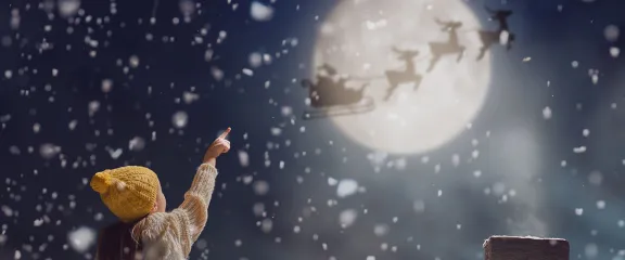 child pointing at Moon as Santa flies past