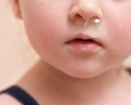 A bubble of snot emerges from a child's nostril