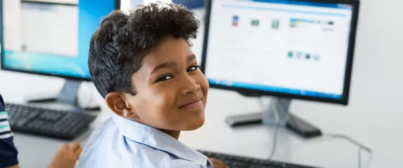 A happy schoolboy working on a desktop computer