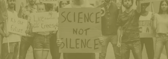 Activists protesting with one holding a sign 'science not silence'