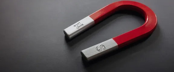 A horseshoe magnet against a grey background