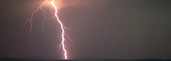 A large flash of white lightning against a dark grey sky