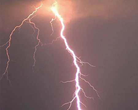 A large flash of white lightning against a dark grey sky