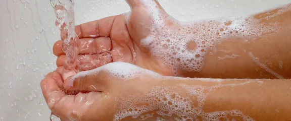 Wrinkly hands under a bath tap