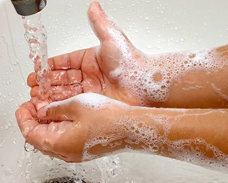 Wrinkly hands under a bath tap