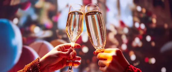 Champagne glasses clink against a festive backdrop
