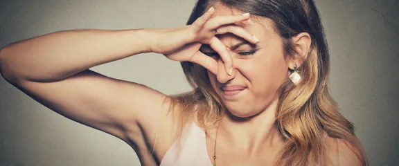 A woman hold her nose in disgust at a smell