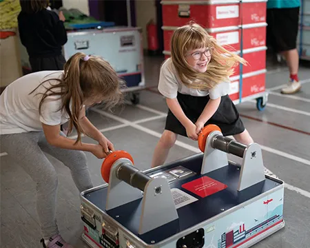 Two schools pupils crank the handles on a science exhibit during an On Tour visit to their school