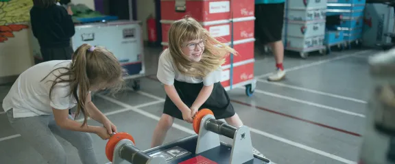 Two schools pupils crank the handles on a science exhibit during an On Tour visit to their school