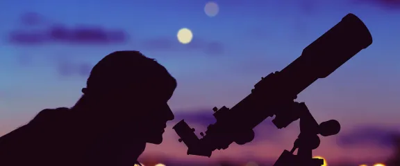 A woman looking at the night sky though a telescope