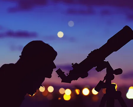 A woman looking at the night sky though a telescope