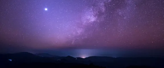 The milky way and night sky above mountains and water