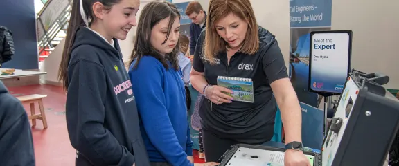 An expert from Drax guides school pupils in using an interactive exhibit