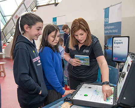 An expert from Drax guides school pupils in using an interactive exhibit