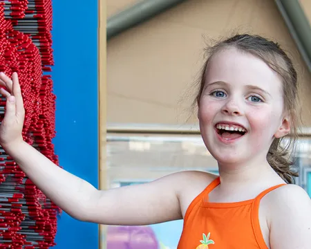 A child smiling whilst interacting with the pin wall exhibit