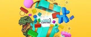 Open turquoise gift box with Glasgow Science Centre card; T‑rex, balloon dog, cake and colorful bricks bursting out.