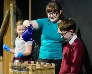 A presenter pours water onto a castle in a science show experiment