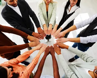 A circle of adults put their arms into the middle