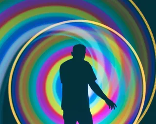 A person in silhouette is circled by a swirling rainbow of light