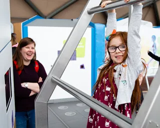 A child tests their grip endurance on our hang time exhibit